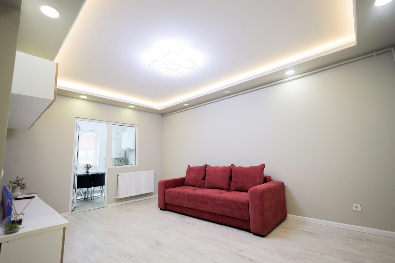 Living cu canapea roșie și tavan cu scafă luminoasă