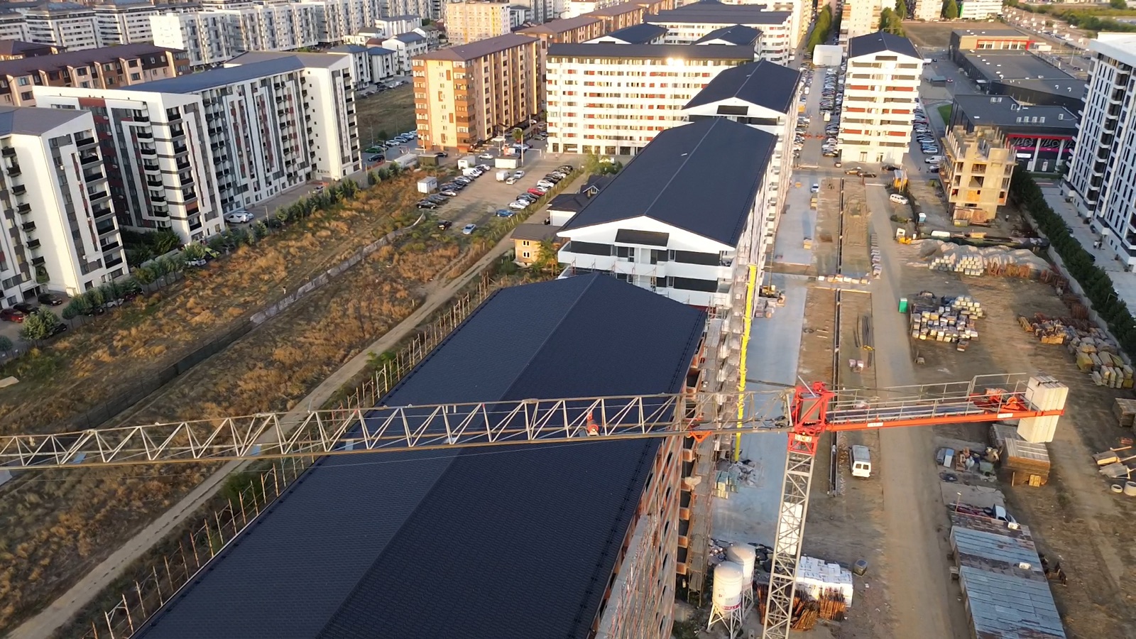 Stadiu de construcție: macara peste trupele de clădiri cu acoperiș în montaj